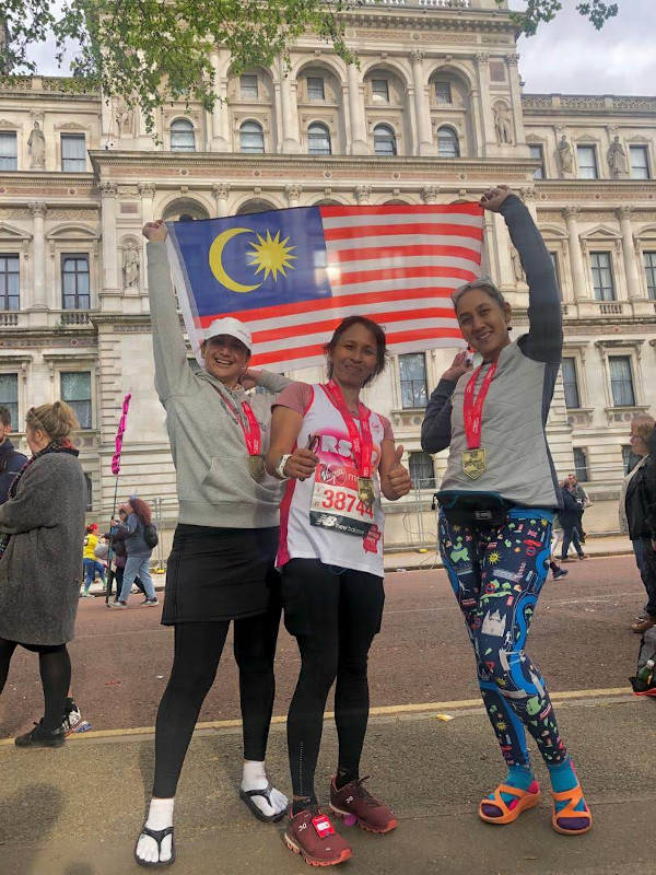 Three friends who managed to gain entry to the race together; proud to wave the flag at the end of the run!
