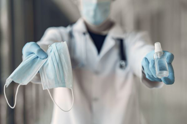 blurred image of a nurse handing over masks and hand sanitizer 