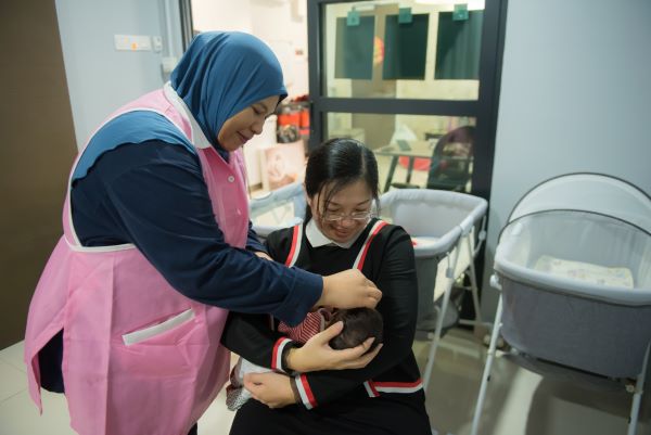 lactation consultant helping a mother breastfeed her baby.