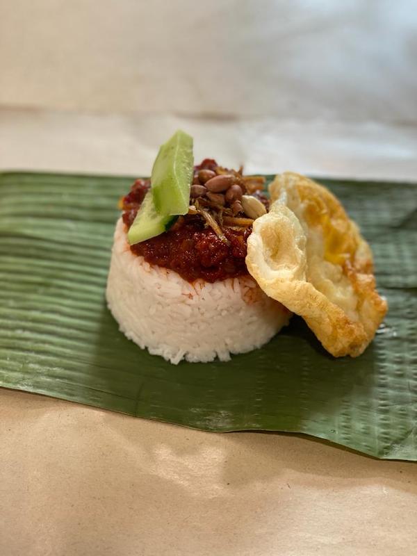 Rice with sambal on top, cucumber slices, fried anchovies and peanuts and a fried egg on the side. My mum's nasi lemak.
