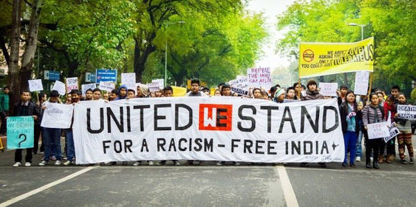 A group of protesters in India stretching across a banner with an anti-racism message.