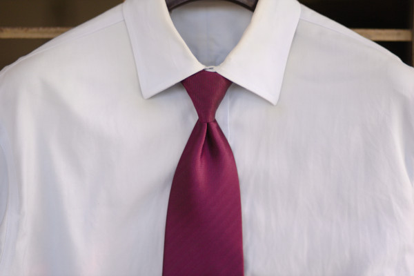 Solid light blue shirt on a hanger, with a conservative solid maroon tie.