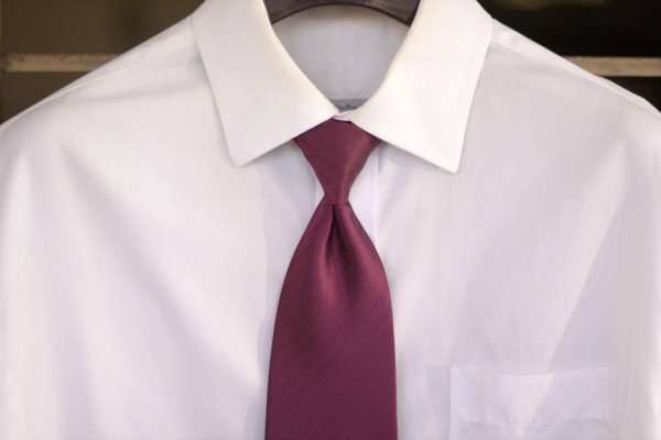 Solid white shirt on a hanger, with a conservative solid maroon tie.