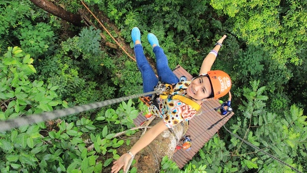 A smiling girl indulging in extreme activities like this ziplining obstacle course.