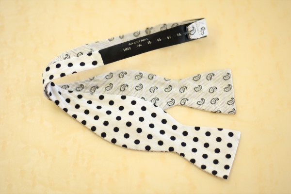 Close up of a self-tie bow tie, laid flat on the table, showcasing the adjustable neckband 