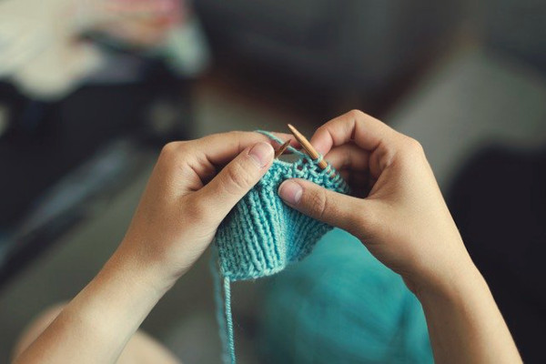 Point of view of the person hand-knitting with a pair of knitting needles.