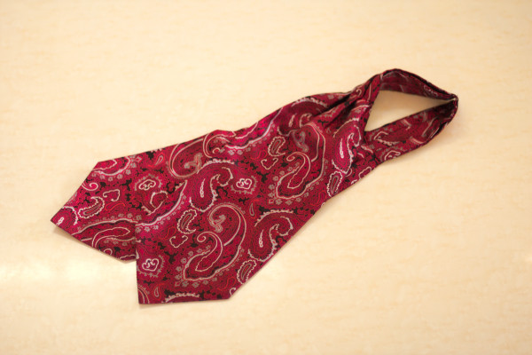 Image of a red paisley cravat, laid flat on a table.