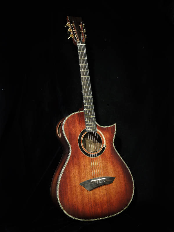 The front side of a reddish-brown Mahogany OM-Cutaway handmade guitar. 