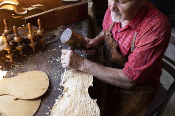 A luthier sits in his workshop while crafting a handmade violin.