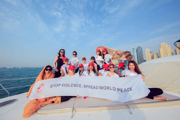 Michelle Chan with a group of UNG 2019 contestants holding a white banner that reads, "stop violence, spread world peace."