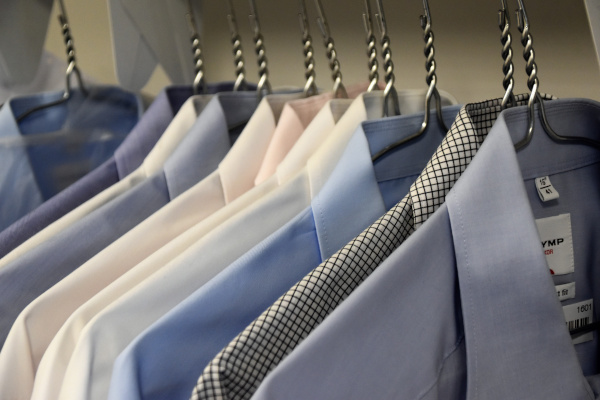 Different types of shirts hanging neatly in a cupboard. This represents the various types of shirts that we all have on rotation in our own wardrobe.