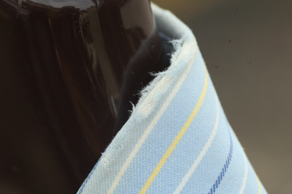 Close-up on the collar fold of the light blue stripe shirt. The fraying is very obvious, with the structural canvas visible underneath the frayed fibres.