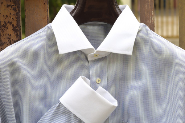 An example of a contrasting collar shirt. The body is a fine blue/grey stripe, with solid white collar. Also displaying a solid white double cuff too.