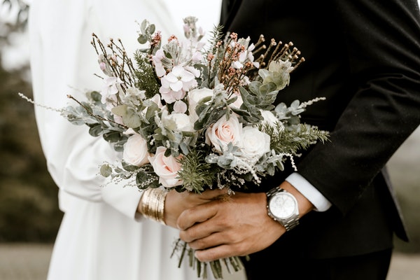 A newly married couple holding a bouquet of flowers together.