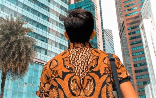 A man wearing a batik shirt looking out to an array of buildings.