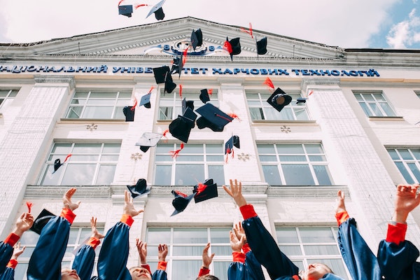 tertiary students throwing their graduation caps into the air
