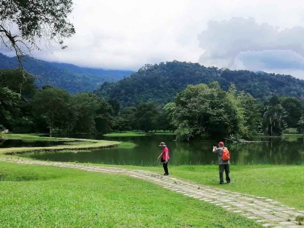 An elderly couple taking photos of the scenic Taiping Lake Gardens along the walkway leading to another end of the garden
