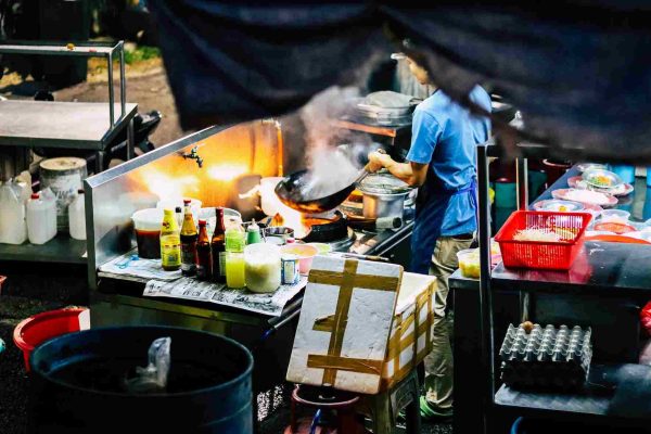 A hawker tossing the ingredients in the wok over the flame