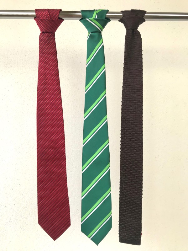 Three ties - red with small repeating patterns, medium green with lime green and white regimental stripes, and solid charcoal brown knit tie.