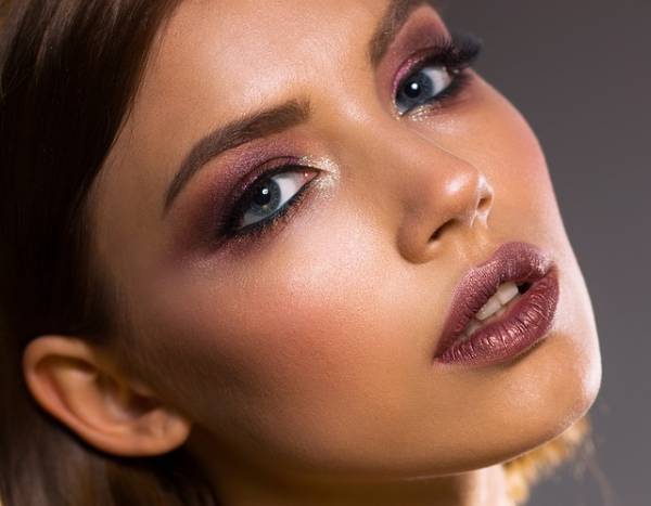 A female commercial model with full makeup on, displaying a pair of burgundy-coloured sensual, luscious lips 