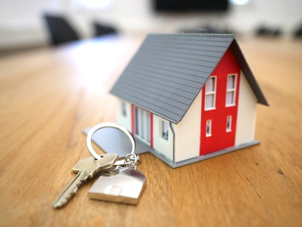 A model house, and a key on a table, symbolising the ownership of a home.