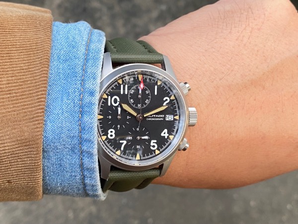 Close-up to the wrist, with a camel coloured corduroy sport jacket. Faded indigo denim shirt sleeve. And the ML1868 field watch with olive green sailcloth strap.