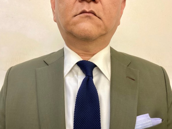 Close-up of the chest displaying a typical business formal outfit, emphasising the knit tie in place of a more common woven tie.