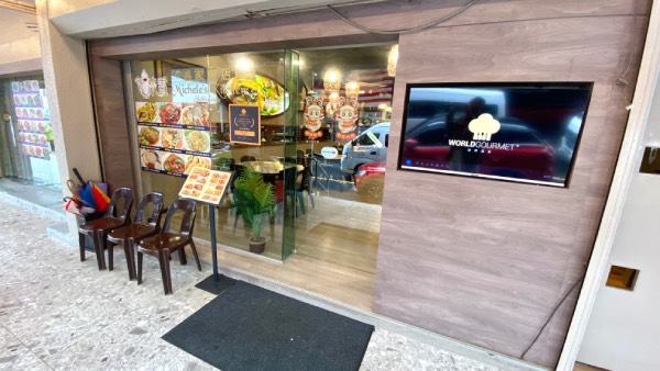 The frontage of Michele's Kitchen, displaying a menu on a stand, with some chairs for when the customers are waiting for tables.