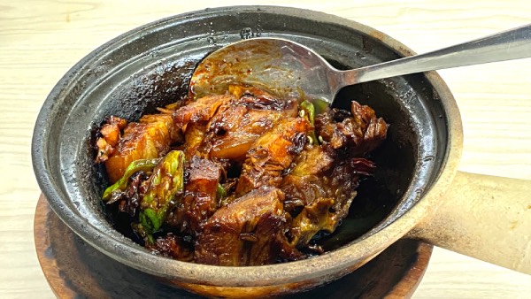 Close-up of a dry braised bak kut teh in a claypot. Cuts of pork, caramelised in spices and dark soy sauce.