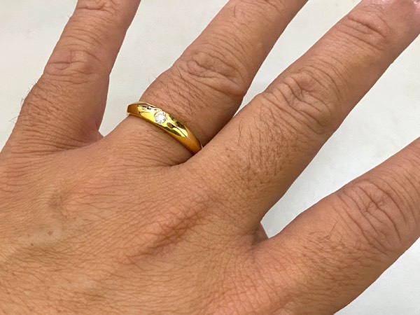 Close-up to the back of the hand, showing a gold wedding band, worn on the ring finger.